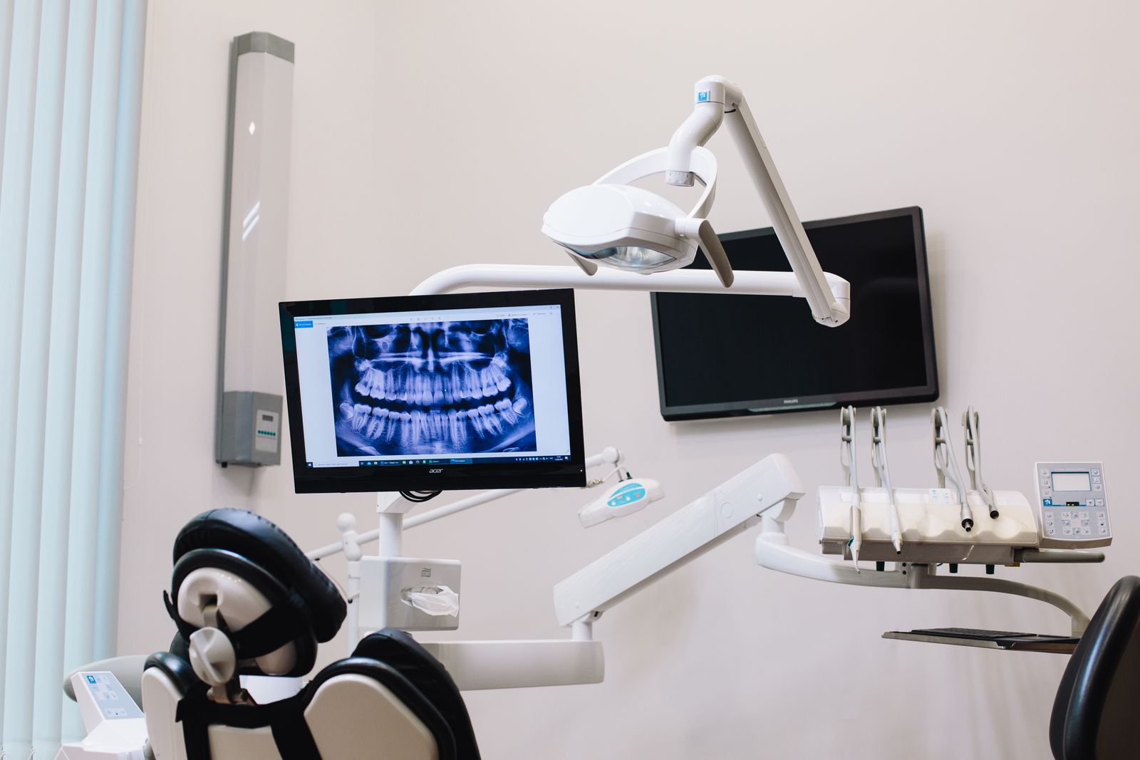 Um consultório dental moderno com exibição de raio-X em um monitor e equipamentos dentais avançados.